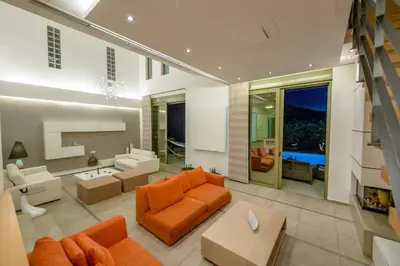 a living room with an orange couch and chairs at Filerimos Oasis Villa in Ialyssos