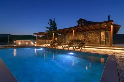 a swimming pool in front of a house at night at ElaionHill-villa in Gennadi