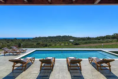 a swimming pool with lounge chairs and a swimming pool at ElaionHill-villa in Gennadi