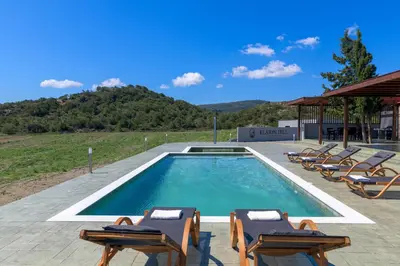 a swimming pool with lounge chairs next to a building at ElaionHill-villa in Gennadi