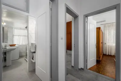 a bathroom with white walls and a mirror at Plumeria Apartment in Rhodes Town