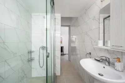 a white bathroom with a sink and a shower at Plumeria Apartment in Rhodes Town