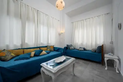 a living room with two blue couches and a table at Plumeria Apartment in Rhodes Town