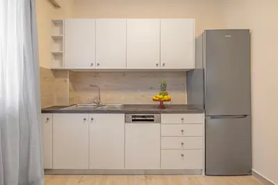 a kitchen with white cabinets and a stainless steel refrigerator at City Choice 2 Live - Sofouli 15 in Rhodes Town
