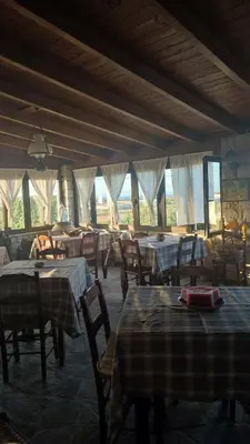 a dining room with tables and chairs and windows at Liros in Kamiros