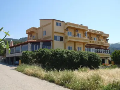 a large yellow building with bushes in front of it at Liros in Kamiros