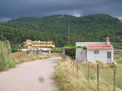 a dirt road next to a house and a mountain at Liros in Kamiros