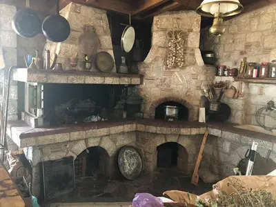 a kitchen with a stone fireplace with pots and pans at Liros in Kamiros