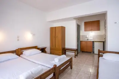 a bedroom with two beds and a kitchen at Nikos BnB in Faliraki