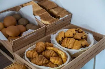 three wooden boxes filled with different types of bread and pastries at Nikos BnB in Faliraki