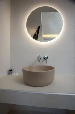 a sink in a bathroom with a circular mirror at Nikos BnB in Faliraki