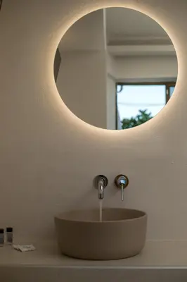 a bathroom sink with a round mirror above it at Nikos BnB in Faliraki