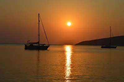two boats sitting in the water at sunset at Sunrise Apartments in Livadia