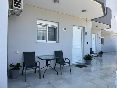 a table and chairs in a room with a white wall at CARISSA SUITES a in Afantou