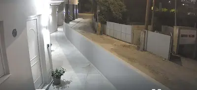 an empty alley with a white fence and a potted plant at CARISSA SUITES a in Afantou