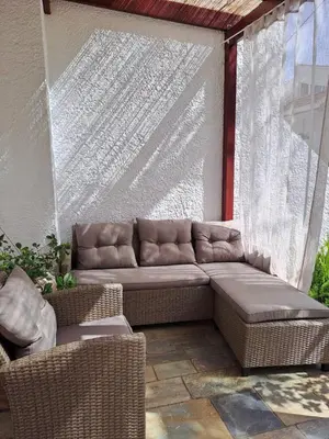 acovered patio with a couch and wicker chairs at Bella Vita Ixia in Ixia
