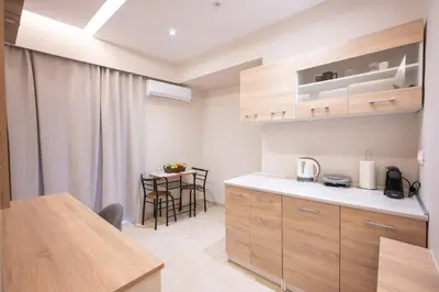 a kitchen with wooden cabinets and a small table at Blue Wave Suites - Ixia in Ialyssos