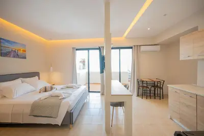 a bedroom with a bed and a kitchen with a table at Blue Wave Suites - Ixia in Ialyssos