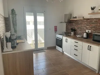 a kitchen with white cabinets and a brick wall at Telis House in Rhodes Town