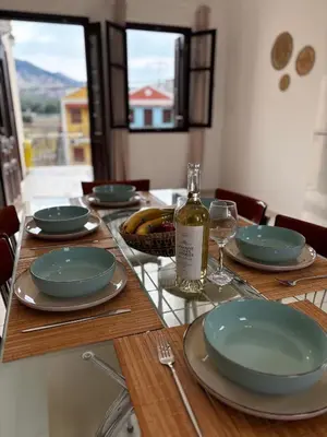 a wooden table with plates and a bottle of wine at Amelia's Home in Symi
