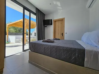 a bedroom with a bed and a large window at Myrteni Pool Villas in Ialyssos