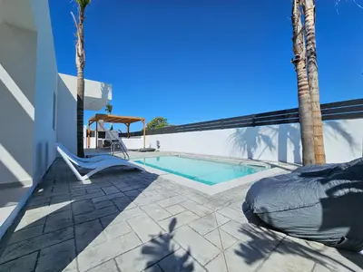 a swimming pool with a chair next to a house at Myrteni Pool Villas in Ialyssos