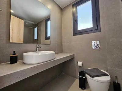 a bathroom with a sink and a toilet and a mirror at Myrteni Pool Villas in Ialyssos