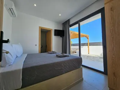 a bedroom with a bed and a view of the beach at Myrteni Pool Villas in Ialyssos
