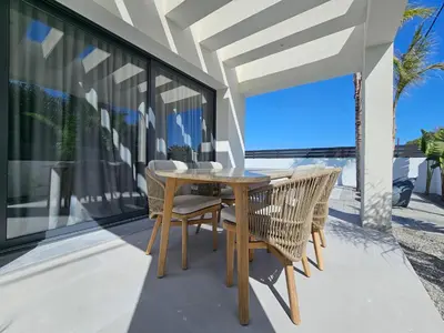 a dining table and chairs on a balcony with a view at Myrteni Pool Villas in Ialyssos