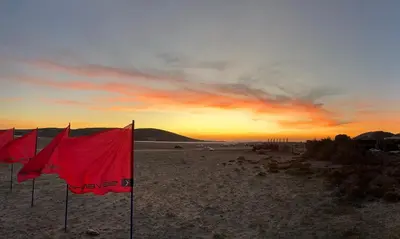 a group of red flags on the beach at sunset at Kertenia - Villa Vayu in Kattavía