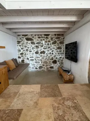 a living room with a couch and a stone wall at Kertenia - Villa Vayu in Kattavía
