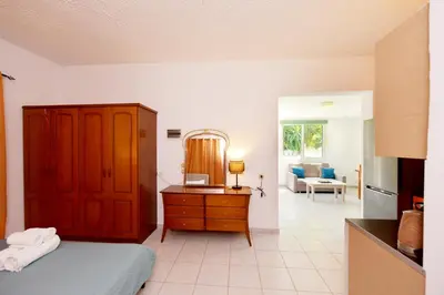 a bedroom with a bed and a dresser and a living room at Liri family paradise Danis house in Ixia
