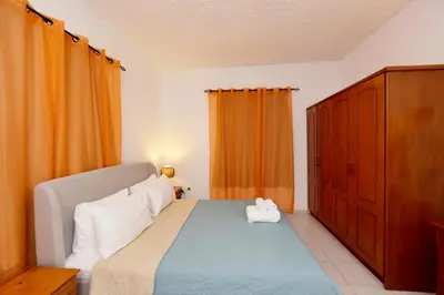 a bedroom with a bed and an orange curtain at Liri family paradise Danis house in Ixia