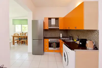 a kitchen with orange cabinets and a stainless steel refrigerator at Liri family paradise Danis house in Ixia