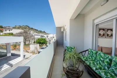a balcony with a couch and a large window at Sokrates Residence in Afantou