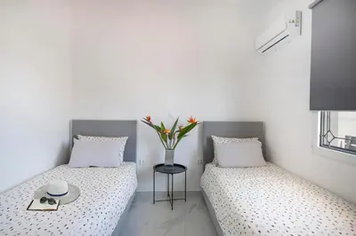 two beds in a room with a vase of flowers at Sokrates Residence in Afantou