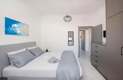 a white bedroom with a bed and a dresser at Sokrates Residence in Afantou