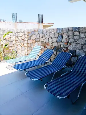 three blue chairs sitting next to a stone wall at Azure Mirage Home Adults Only Private Seaside Villa w Garden and Parking in Faliraki