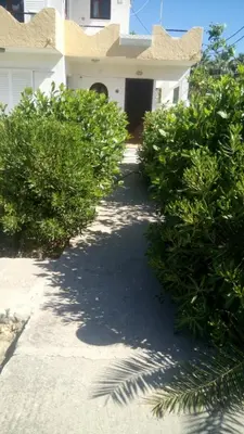 a driveway leading to a white house with green bushes at Sunset Beach Studio in Kremasti