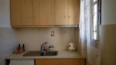 a kitchen with wooden cabinets and a sink and a window at Sunset Beach Studio in Kremasti