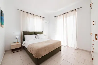 a white bedroom with a large bed with white curtains at Villa Perla in Lardos