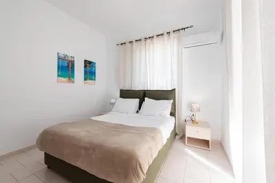 a white bedroom with a large bed and a window at Villa Perla in Lardos