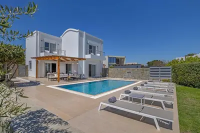 a villa with a swimming pool and lounge chairs at Villa Petalutha Rhodes in Kolimbia