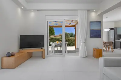 a living room with a flat screen tv and a kitchen at Villa Petalutha Rhodes in Kolimbia