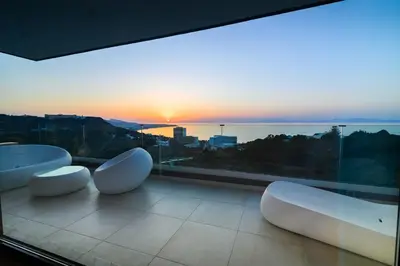 a balcony with two white chairs and a sunset at Aquarama Pool Apt - Orion in Ixia
