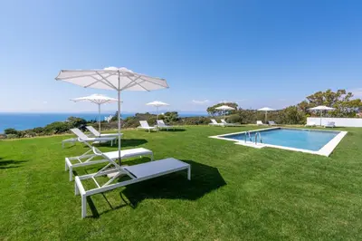 a lawn with chairs and an umbrella and a swimming pool at Aquarama Pool Apt - Orion in Ixia