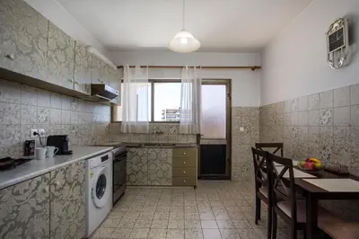 a kitchen with a sink and a table and a stove at Rhodes Marina Apartment in Rhodes Town