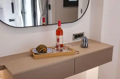 a bottle of wine and glasses on a shelf in a bathroom at Sulaj Apartments in Faliraki