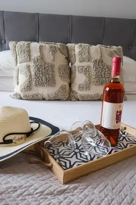a tray with a bottle of wine and glasses on a bed at Sulaj Apartments in Faliraki