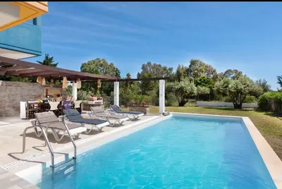 a swimming pool with chaise lounge chairs and a house at Lual Palette Rhodos in Afantou